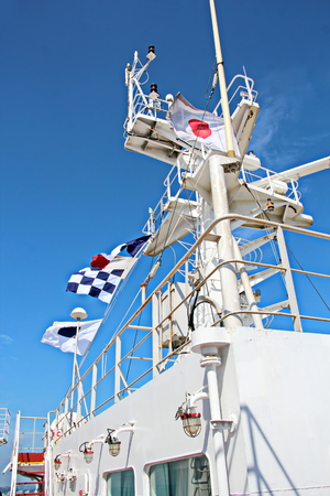 State flags raised on the mast of a merchant ship in the ports of call. Different kinds of flags against the blue sky and clouds.の写真素材