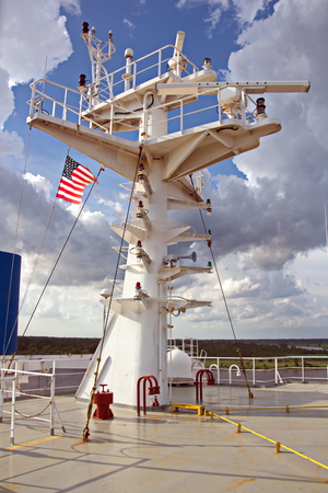State flags raised on the mast of a merchant ship in the ports of call. Different kinds of flags against the blue sky and clouds.の写真素材