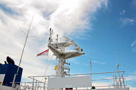 State flags raised on the mast of a merchant ship in the ports of call. Different kinds of flags against the blue sky and clouds.の写真素材