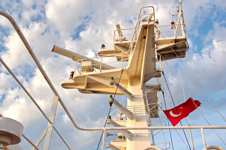 State flags raised on the mast of a merchant ship in the ports of call. Different kinds of flags against the blue sky and clouds.の写真素材