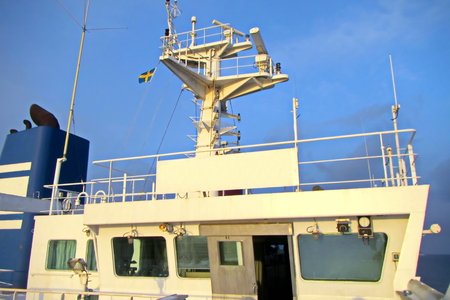 State flags raised on the mast of a merchant ship in the ports of call. Different kinds of flags against the blue sky and clouds.の写真素材