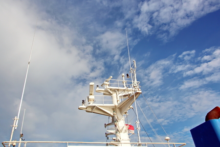 State flags raised on the mast of a merchant ship in the ports of call. Different kinds of flags against the blue sky and clouds.の写真素材