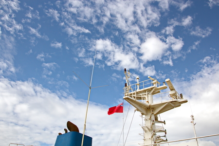 State flags raised on the mast of a merchant ship in the ports of call. Different kinds of flags against the blue sky and clouds.の写真素材