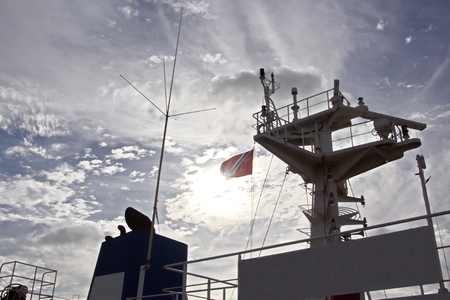 State flags raised on the mast of a merchant ship in the ports of call. Different kinds of flags against the blue sky and clouds.の写真素材