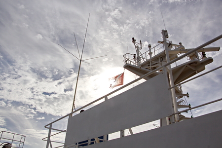 State flags raised on the mast of a merchant ship in the ports of call. Different kinds of flags against the blue sky and clouds.の写真素材