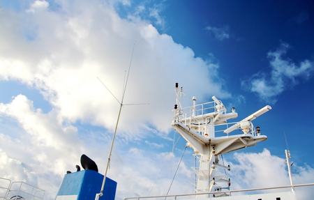 Ship structures, masts, antennas, funnel, ship wheelhouse against the blue sky and clouds.の写真素材