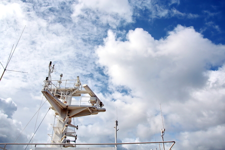 Ship structures, masts, antennas, funnel, ship wheelhouse against the blue sky and clouds.の写真素材