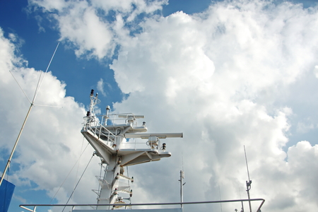 Ship structures, masts, antennas, funnel, ship wheelhouse against the blue sky and clouds.の写真素材