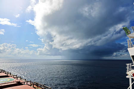 Thunderclouds and rain clouds over the sea horizon and the surface of the Pacific Ocean.