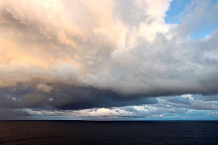 Thunderclouds and rain clouds over the sea horizon and the surface of the Pacific Ocean.