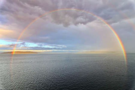 Colorful views of the rainbow against the sky, clouds and sea horizon. Commencement Bay, Tacoma, WA, USAの写真素材