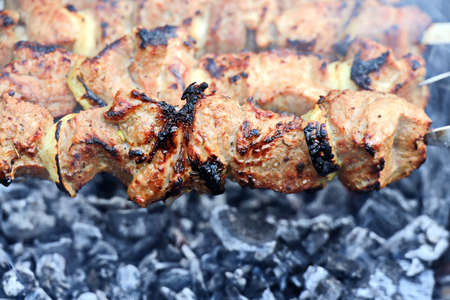 Shish kebab roasting on the grill. Close-up. A dish consisting of small pieces of meat, chicken and...