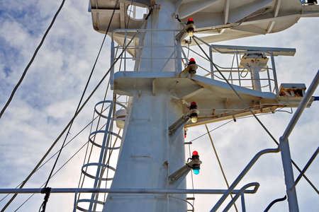 Ship structures, masts, antennas, funnel, ship wheelhouse against the blue sky and clouds.