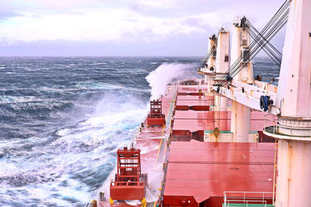 Movement of the vessel in stormy weather, Pacific Ocean. Waves and spray covering the ship during a stormの写真素材
