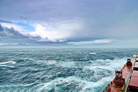 Movement of the vessel in stormy weather, Pacific Ocean. Waves and spray covering the ship during a stormの写真素材