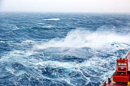Storm waves in the world ocean. Kind of waves, crests, splashes, foam against the background of the sea and blue sky.の写真素材