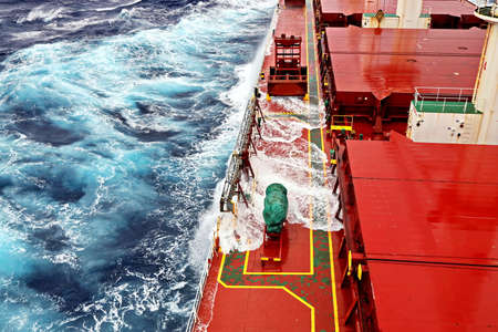 Movement of the vessel in stormy weather, Pacific Ocean. Waves and spray covering the ship during a...