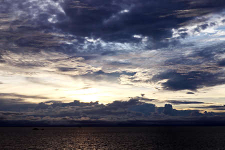 Sunset in the open ocean. Colorful views of the surface of the water and the sky with clouds over...