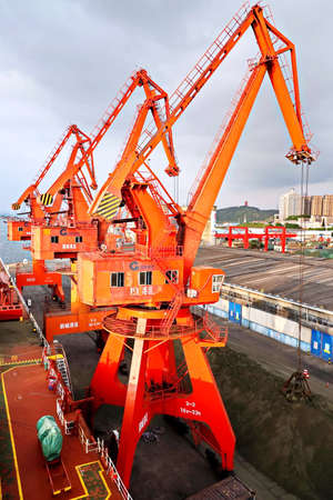 Fangcheng, China, September 30,2020. Cargo terminal for unloading bulk cargoes by shore cranes and grabs.のeditorial素材