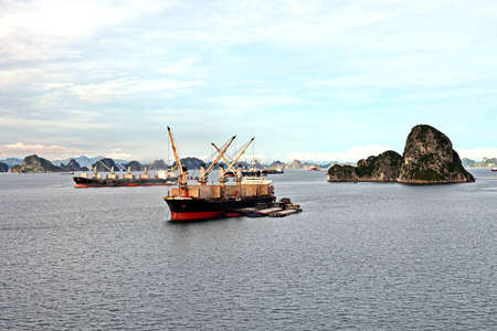 Seagoing vessels, barges, tugboats and small boats at the roadstead of Halong bay under cargo...