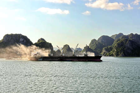 Seagoing vessels, barges, tugboats and small boats at the roadstead of Halong bay under cargo...