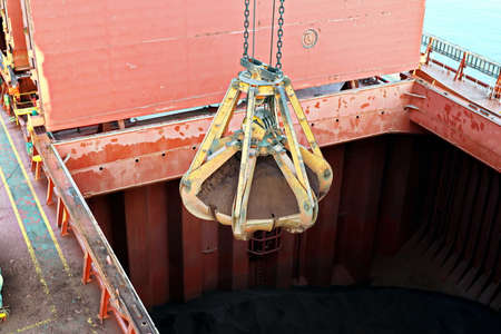 Cargo terminal for unloading bulk cargo of iron ore by shore cranes and grabs. Views of cargo...