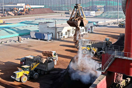 Cargo terminal for unloading bulk cargo of iron ore by shore cranes and grabs. Views of cargo...