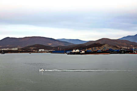 Container vessels, bulk carrier and tugboats at the port under cargo operations and underway. Port of Vostochnyy. Russia, December, 2020の写真素材