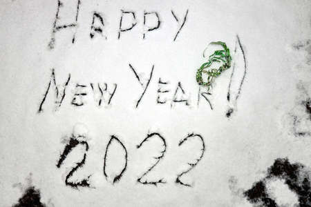 Inscription Happy New Year 2022 and Marry Christmas on natural snowy surface in wintertime. Text, winter holiday background with copy space on snow. hand writing, text,の写真素材