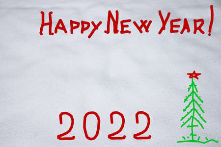 Inscription Happy New Year 2022 and Marry Christmas on natural snowy surface in wintertime. Text, winter holiday background with copy space on snow. hand writing, text,の写真素材