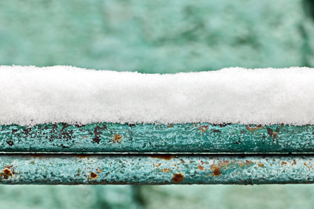 The metal bars of the fence are painted blue and white, covered with snow and ice. Close-up.の写真素材