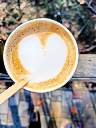 Cup of coffee with heart shape on wooden table in forest.の写真素材