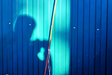 Shadow of a man on a background of a blue wooden wall.の写真素材
