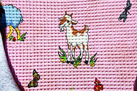Close up detail of a goat embroidery on a pink background