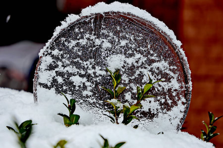 Snow covered wooden barrel on the background of a red brick wall.の写真素材