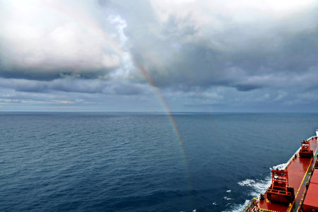 Rainbow over the sea and cargo ship in the gulf of Thailand