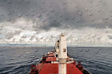 Oil tanker ship in the sea with rain drops and cloudy sky.