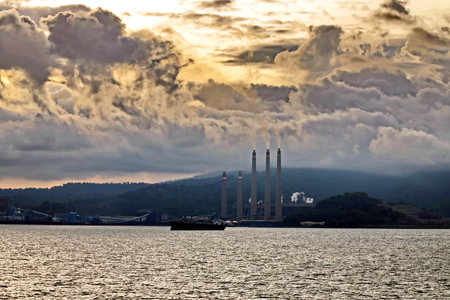 Coal power plant in the sea with a ship in the backgroundの写真素材