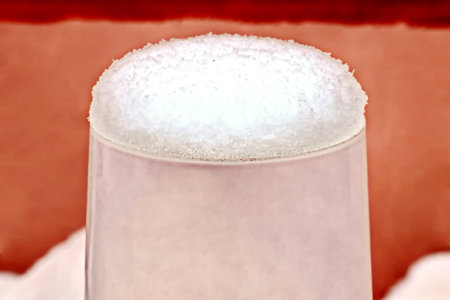 Close-up shot of a glass with foam on a red background