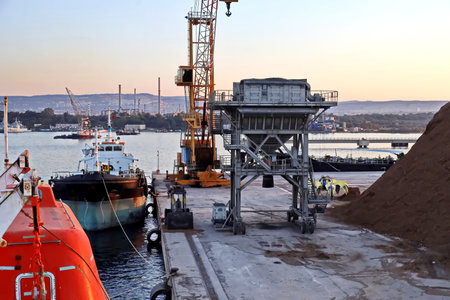 Bulk cargo ship under crane bridge at sunset, Odessa, Ukraineの写真素材