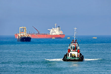 Tugboat assisting bulk cargo ship to harbor quayside, Australia