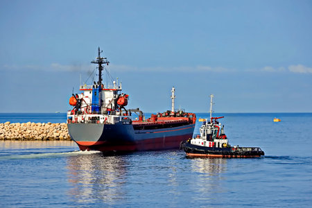 Tugboat assisting bulk cargo ship to harbor quayside, Odessa, Ukraineの写真素材