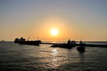 Cargo ship and tugboat in the sea at sunset or sunrise.の写真素材