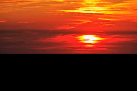 Beautiful sunset over the sea with clouds and sun in the skyの写真素材