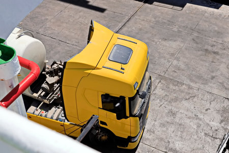 A yellow truck is parked on a concrete surface.