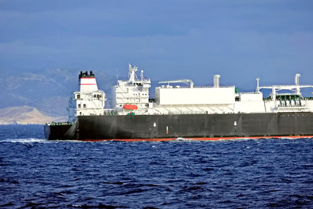 Tugboat assisting bulk cargo ship to harbor quayside.の写真素材