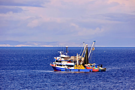 Fishing trawler in the sea on a background of blue skyの写真素材