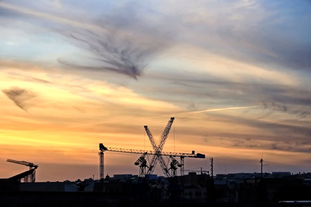 silhouette of construction cranes on the background of the sunsetの写真素材