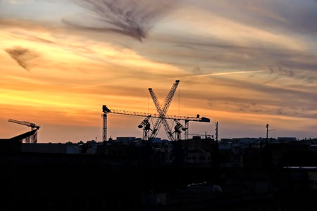 Silhouette of a construction site with cranes at sunset.の写真素材