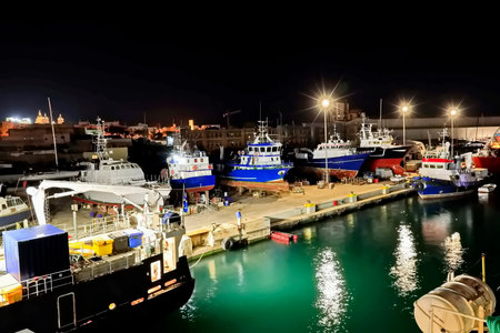 Fishing boats and yachts in the port at night.の写真素材